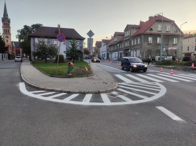 Białe oznakowanie poziome na asfalcie: przejście dla pieszych i powierzchnia wyłączona z ruchu wokół wyspy